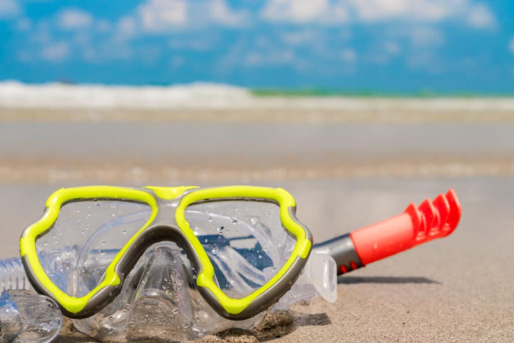 gafas y tubo de snorkel sucios por arena de la playa