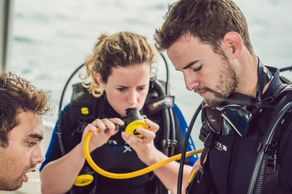 Monitores preparando el equipo para un bautismo de buceo