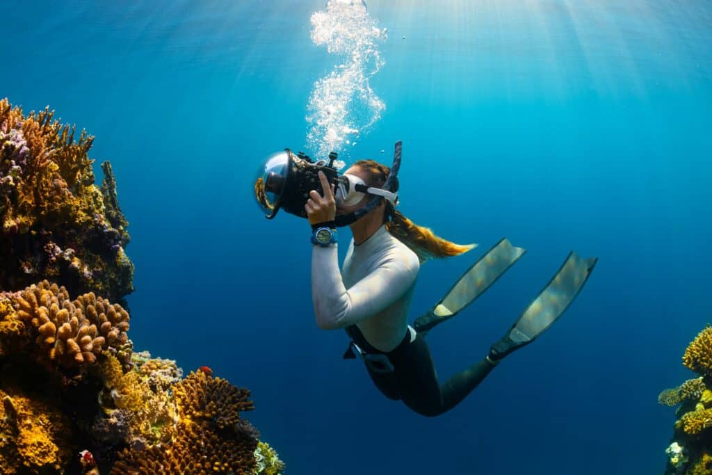 Hombre haciendo snorkel y grabando un coral